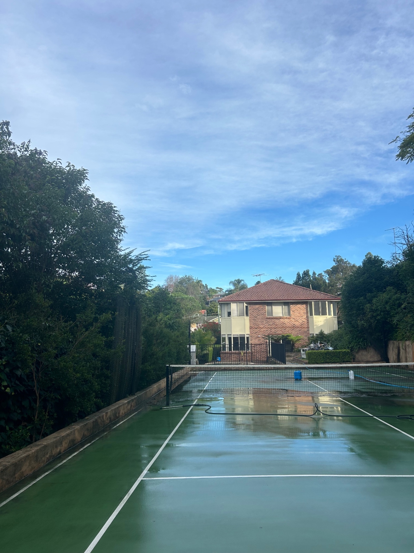 A green tennis court during a pressure clean